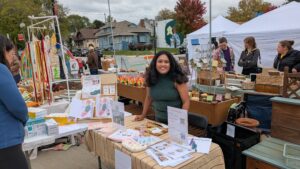 Sowmya founder of Toddlers Love to Cook at market booth with cooking products