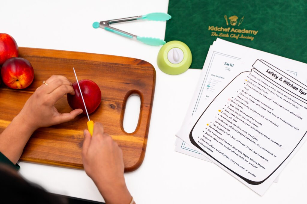 Little hands learning to slice a nectarine on a wooden cutting board