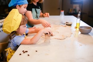 Cute children and their mother making cookies together in a warm kitchen setting.